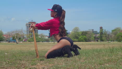 a young woman in a bikini-style baseball uniform standing in a field on the tropical island of trinidad