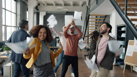 happy office team celebrating success with paper toss