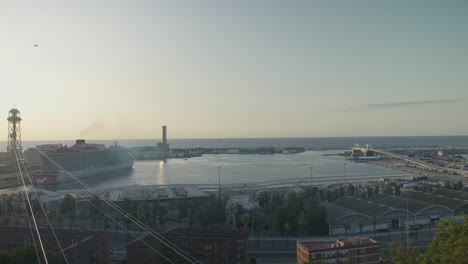 Hi-Res-Cafe-Ledge-Vista-Del-Puerto-Marítimo,-Horizonte-De-La-Ciudad-De-Barcelona-España-Con-Amanecer-Dorado-En-6k-Mientras-Los-Pájaros-Vuelan