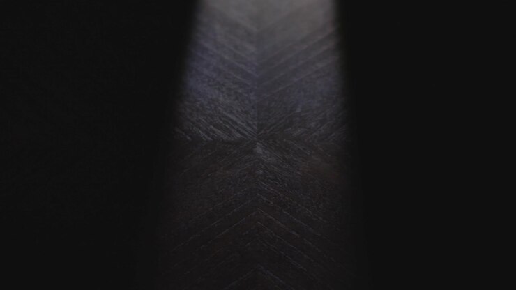 A sticky note that reads "Wednesday" is placed on a table by a hand under dramatic lighting. Shot in slow motion