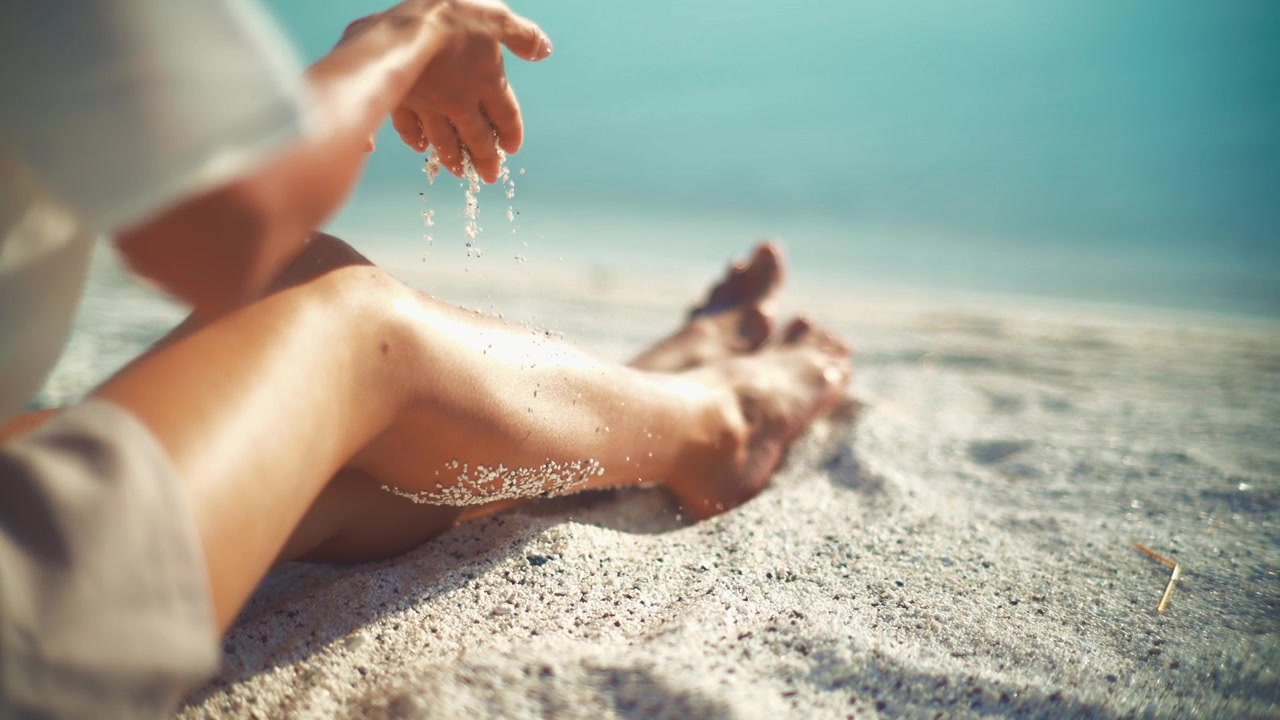 Donna che si rilassa e gioca con la sabbia su una spiaggia soleggiata