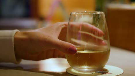 a female with manicured nails, grabbing a glass of wine and removing it from the counter