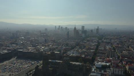 drone ascends to reveal mexico city skyscrapers with famous zocalo in foreground