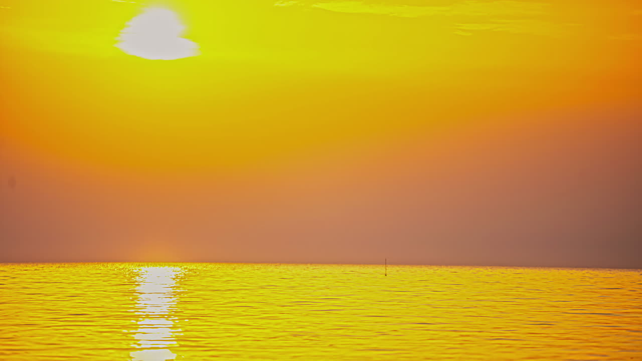 저녁 시간 동안 굴러가는 바다 위의 어두운 클라우드스케이프 하늘을 통해 태양이 지는 저속 촬영