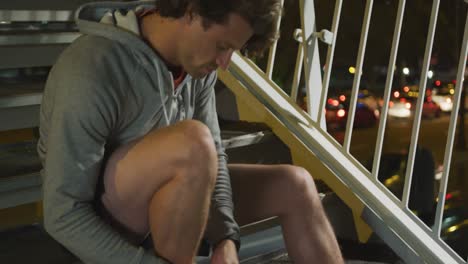 caucasian male smiling and tying his lacet on stairs in the evening