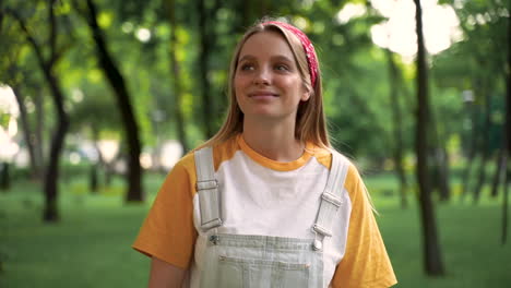 hermosa joven escuchando música con auriculares y caminando en un parque verde