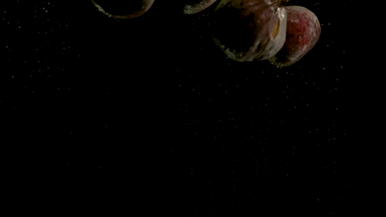 higos cayendo en el agua sobre un fondo negro. brillante video de alta calidad