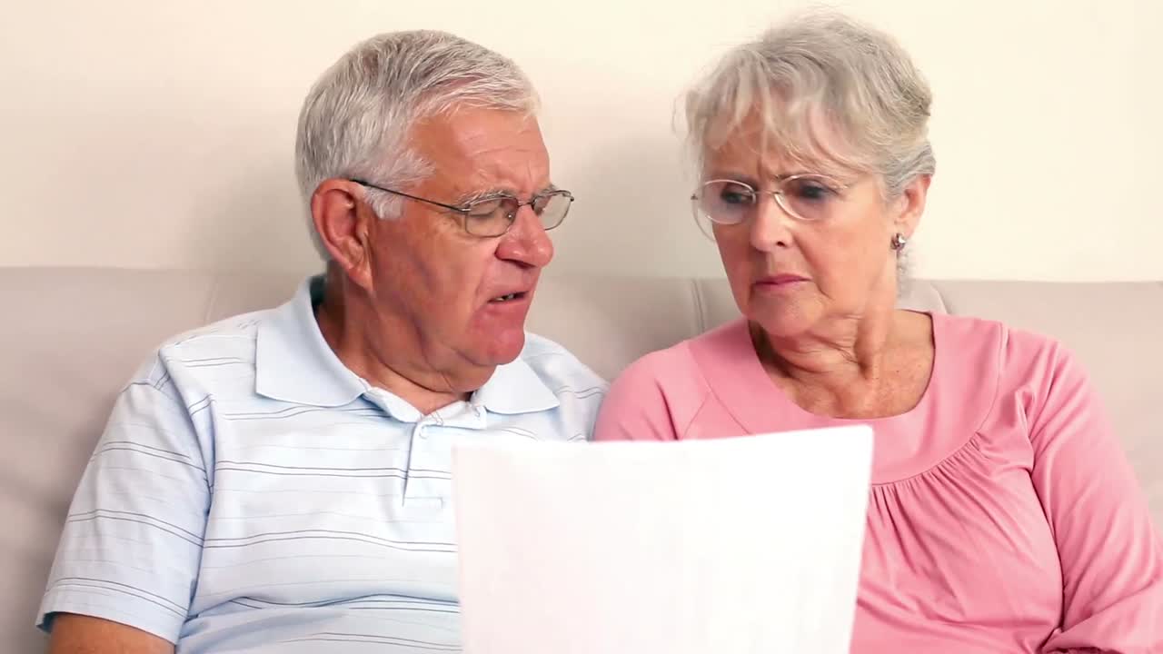 una pareja de ancianos preocupados leyendo un documento