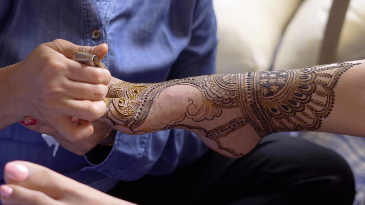 Primo piano sulle gambe durante una cerimonia mehendi di un matrimonio indiano.