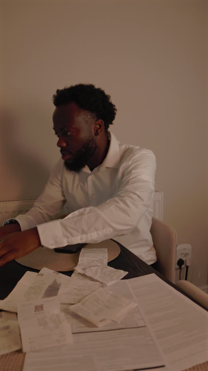 Vertical Video Of Black Male Sorting Through Bill Receipts At Home