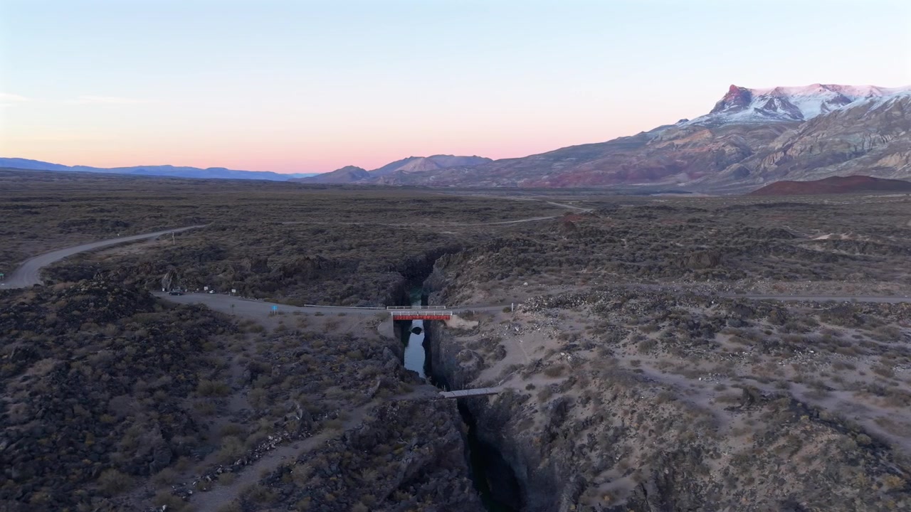 Drone Aerial Establishing of Volcanic Canyon in La Payunia Reserve Mendoza Argentina with Andes Mountains Sunset Background