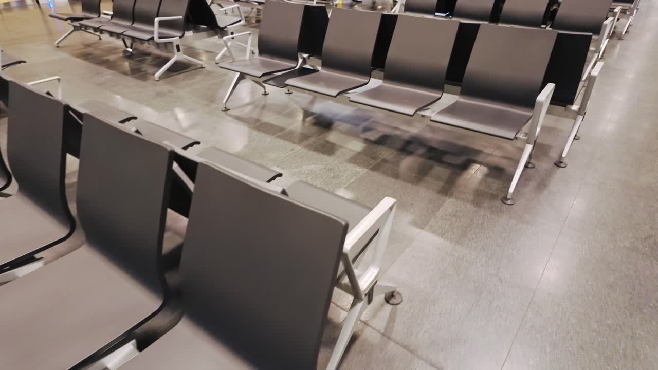 Cámara pasando por filas de asientos vacías del aeropuerto, espacio de terminal desierto, crisis de viajes