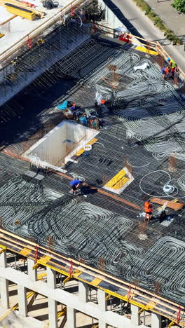 workers placing rebar. construction workers are actively laying rebar on a concrete structure at a busy construction site in the daytime