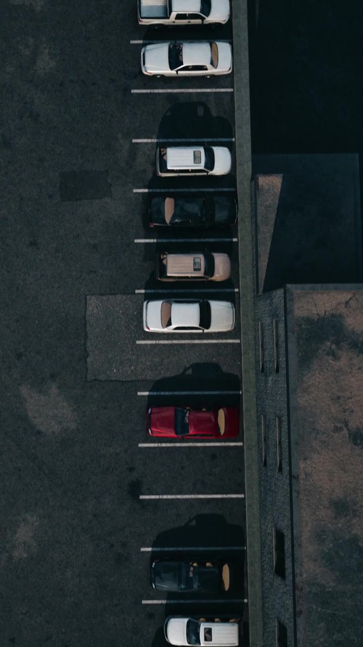Cars parked in a lot next to buildings on a sunny day