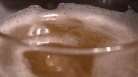 Drops-of-ice-cold-beer-splash-into-glass-of-pale-lager-in-slo-mo