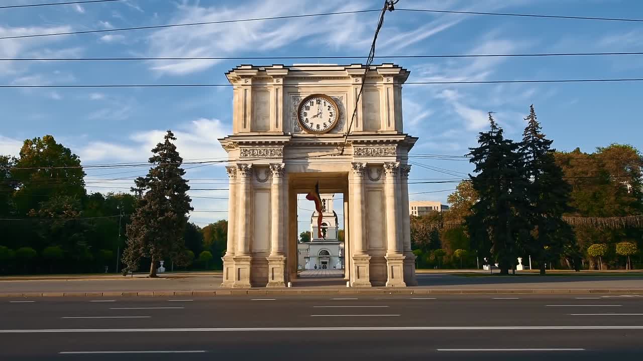 Triumphal Arch with driving cars in center of the city at sunset. Slow motion. Chisinau, Moldova