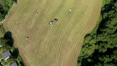aerial birds eye view of tractor pulling trailed across green field in chmielno