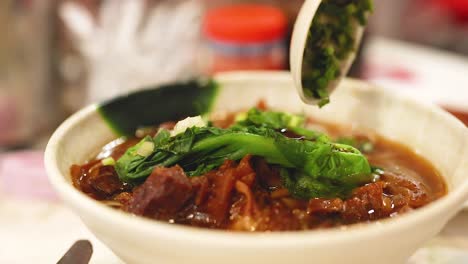 adding herbs to a noodle and meat dish