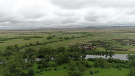 aerial view of a river winding through a green valley with farmhouses and trees