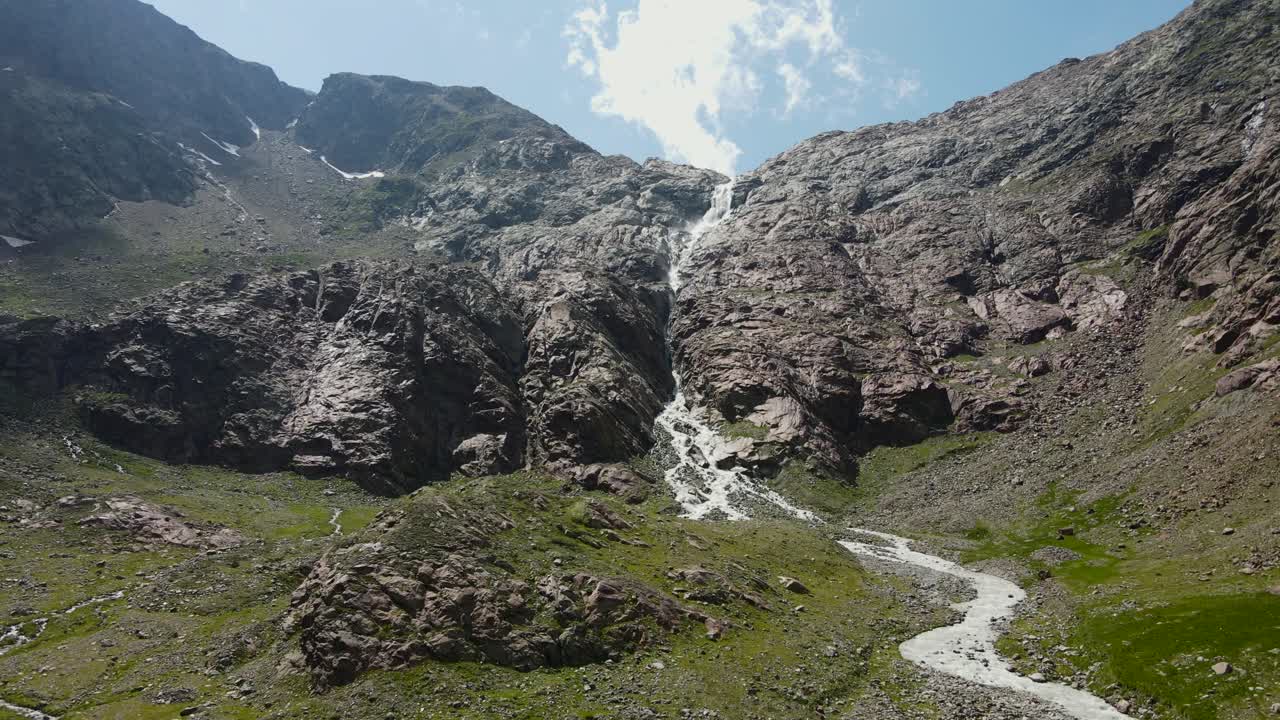 wide angle drone video of the beautiful mountains in northern Italy with a giant waterfall and river. near the dolomites in South Tyrol