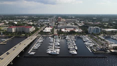 aerial view of bradenton marina with boats docked and the city skyline over the manatee river. crane up day