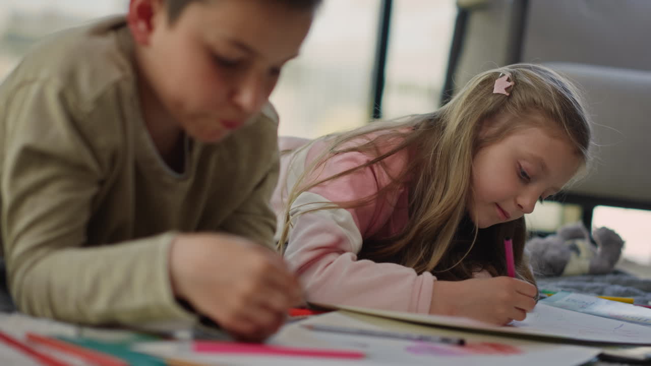 Children lying with sketchbooks. Siblings having interesting activities home
