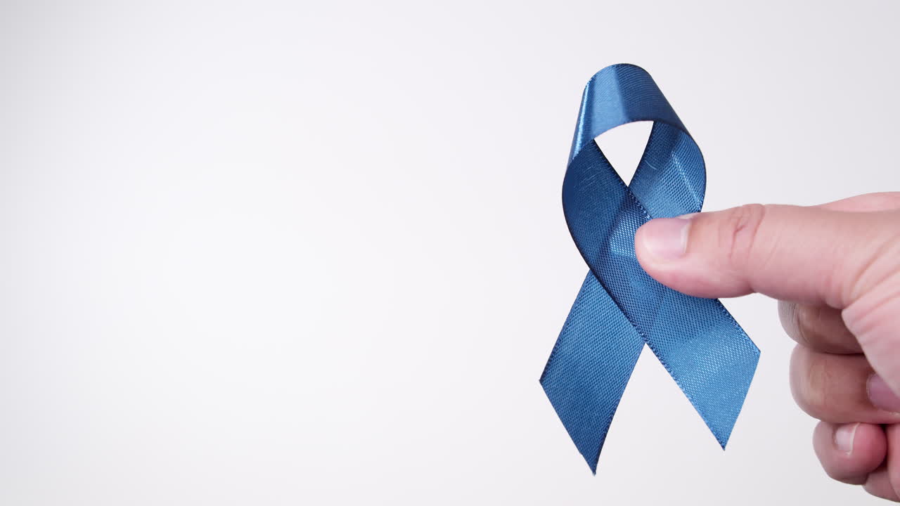 흰색 배경에 파란색 리본을 들고 있는 남성 손