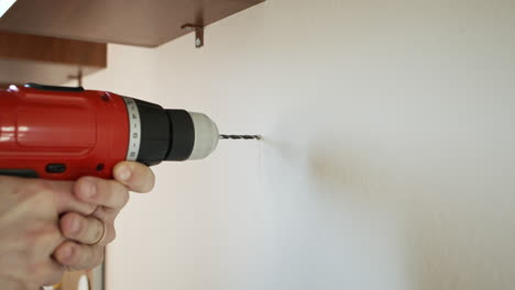 drilling into concrete wall and opening a hole with cordless red power drill in slow mo