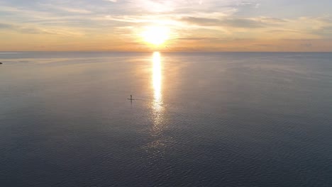 a person paddle boarding at sunset on a calm ocean