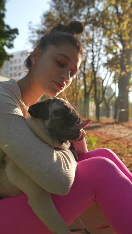 girl hugging a pug puppy in a park