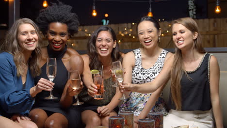 female friends enjoying night out at rooftop bar, slow motion