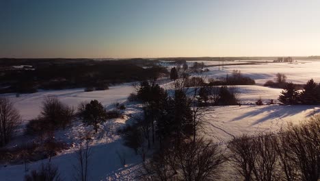 Wunderschöne-Luftaufnahme-Von-Schneebedeckten-Feldern-Und-Wäldern-In-Der-Nähe-Des-Zugefrorenen-Flusses-Sventaja-An-Sonnigen-Wintertagen,-Goldene-Stunde,-Weitwinkel-Drohnenaufnahme-In-Bewegung