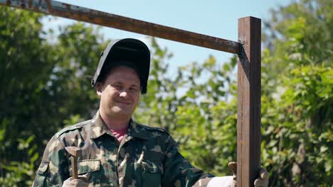 smiling worker taps on finished country house fence carcass