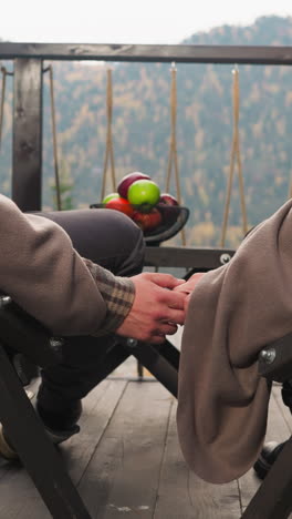 couple joins hands sitting on hotel terrace closeup. boyfriend holds woman hand gently resting together at luxury eco resort. romantic vacation