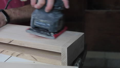 finish sanding the wood filler on wooden floating shelves in preparation to be stained and hung in a remodeled bathroom