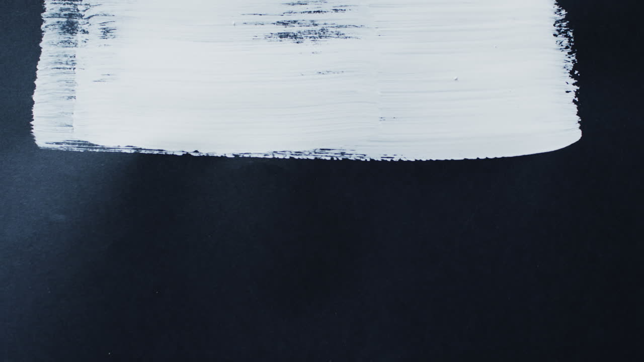 primer plano de una franja de pintura blanca sobre un fondo negro con espacio de copia, cámara lenta
