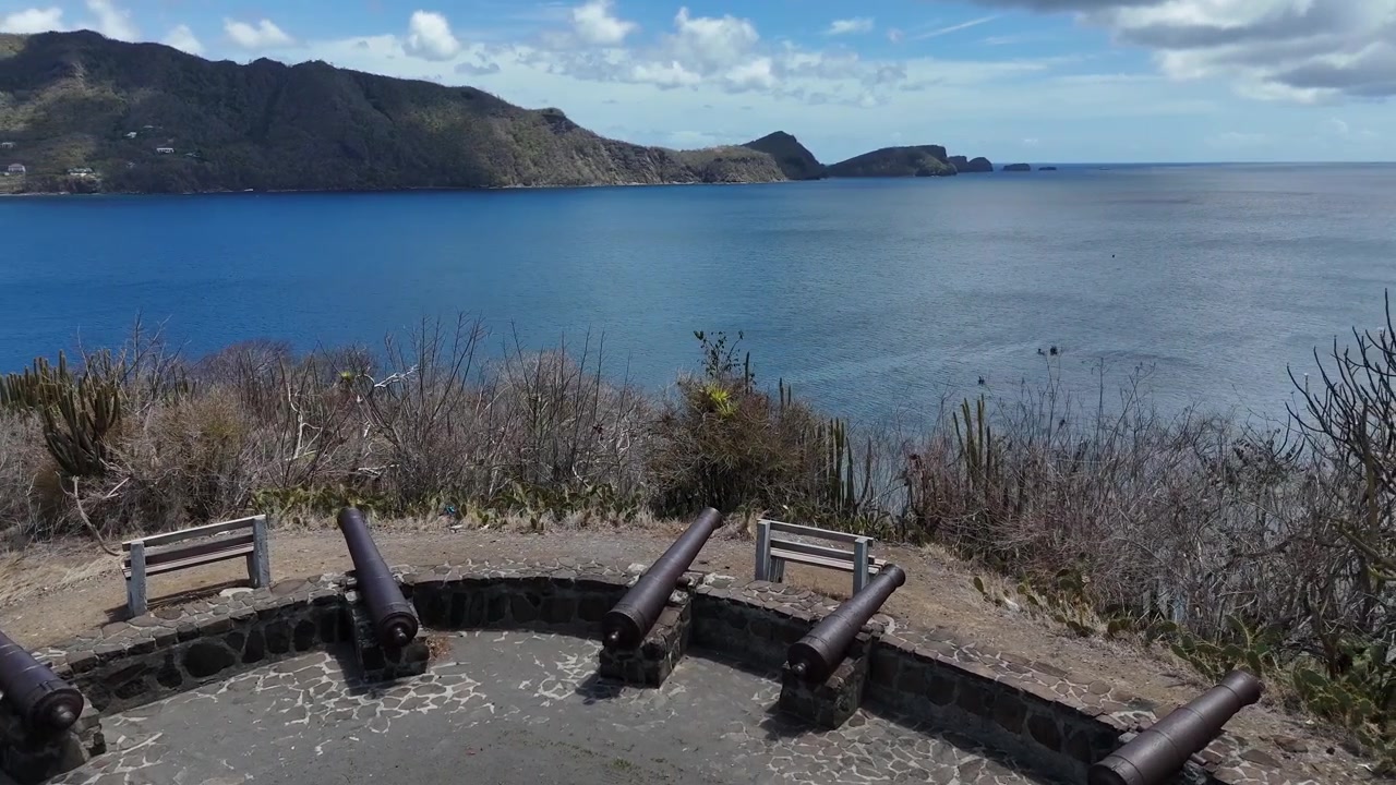 Panoramic drone perspective from a coastal stone fortification or viewpoint looking out at the deep blue Caribbean horizon on Bequia Island