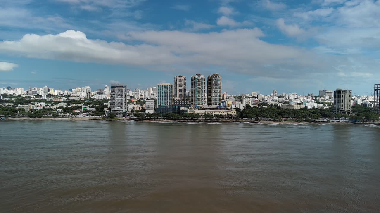 Wide aerial drone view of the Santo Domingo city skyline along the Malecón. High-rise buildings line the Caribbean coast in the capital of the Dominican Republic