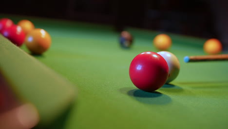 a red ball is potted on a green pool table