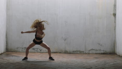 mujer bailarina hermosa joven bailarina de calle caucásica realizando movimientos contemporáneos disfrutando de la expresión de la danza moderna practicando en un almacén grungy