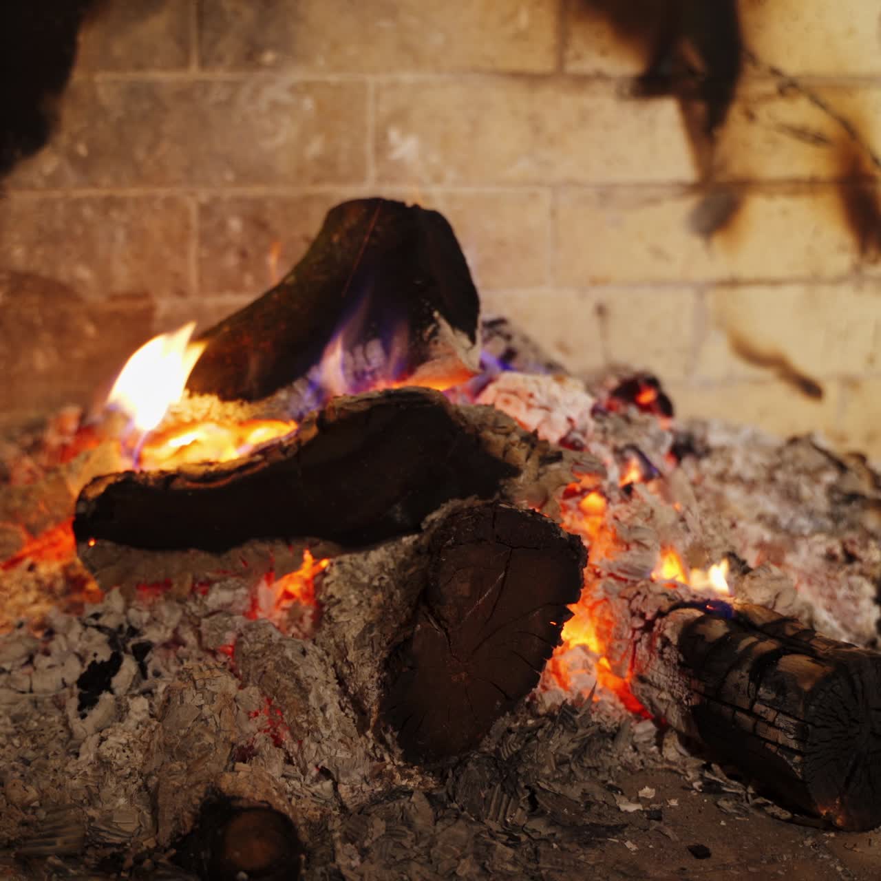Cozy fireplace. Smoldering logs in ash. Embers of burnt-out fire in fireplace at home. Background of burning wood in slight flame. Close-up.