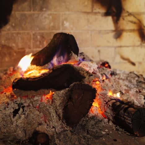 cozy fireplace. smoldering logs in ash. embers of burnt-out fire in fireplace at home. background of burning wood in slight flame. close-up.