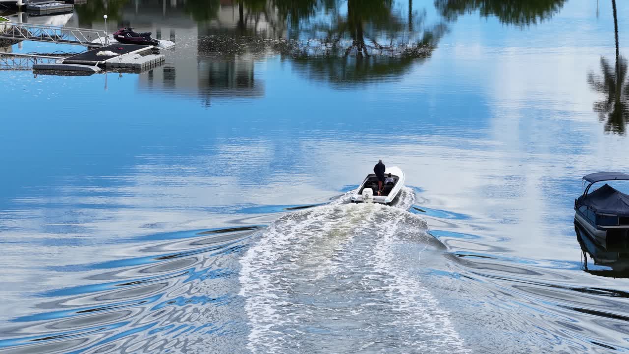 A speedboat navigates serene Gold Coast canals, reflecting clear skies and luxury homes. Dynamic movement captured in bright daylight