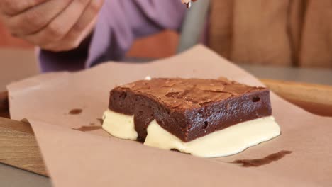 woman eating a chocolate brownie with cream