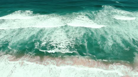 aerial drone showing the endless wild sea waves breaking on the sandy coast in slow motion