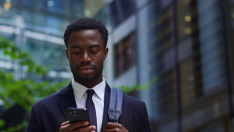 Young-Businessman-Wearing-Suit-Using-Mobile-Phone-Outside-Offices-In-The-Financial-District-Of-The-City-Of-London-UK-1