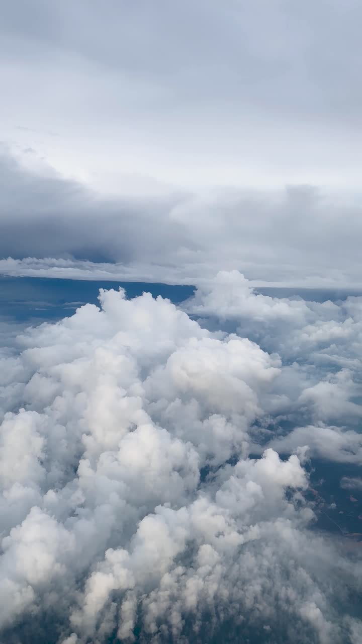Experience a mesmerizing vertical video of towering cumulus clouds from an airplane window, offering a breathtaking aerial perspective ideal for mobile viewing and social media