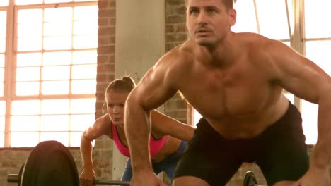 hombre y mujer en forma levantando una barra