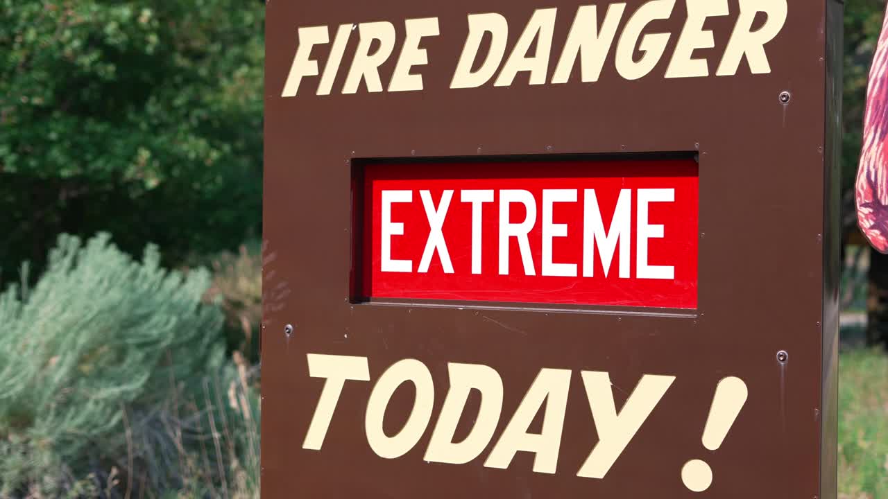 peligro de incendio extremo hoy cartel rojo y blanco en una placa de metal marrón con arbustos arbustos y árboles que soplan en la brisa en el fondo plano amplio en el parque nacional en ogden, utah