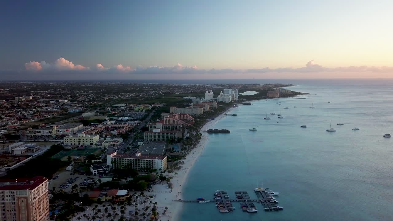 일몰 동안 캐리비안 바다에서 보트와 팜 비치에서 아루바의 해안선